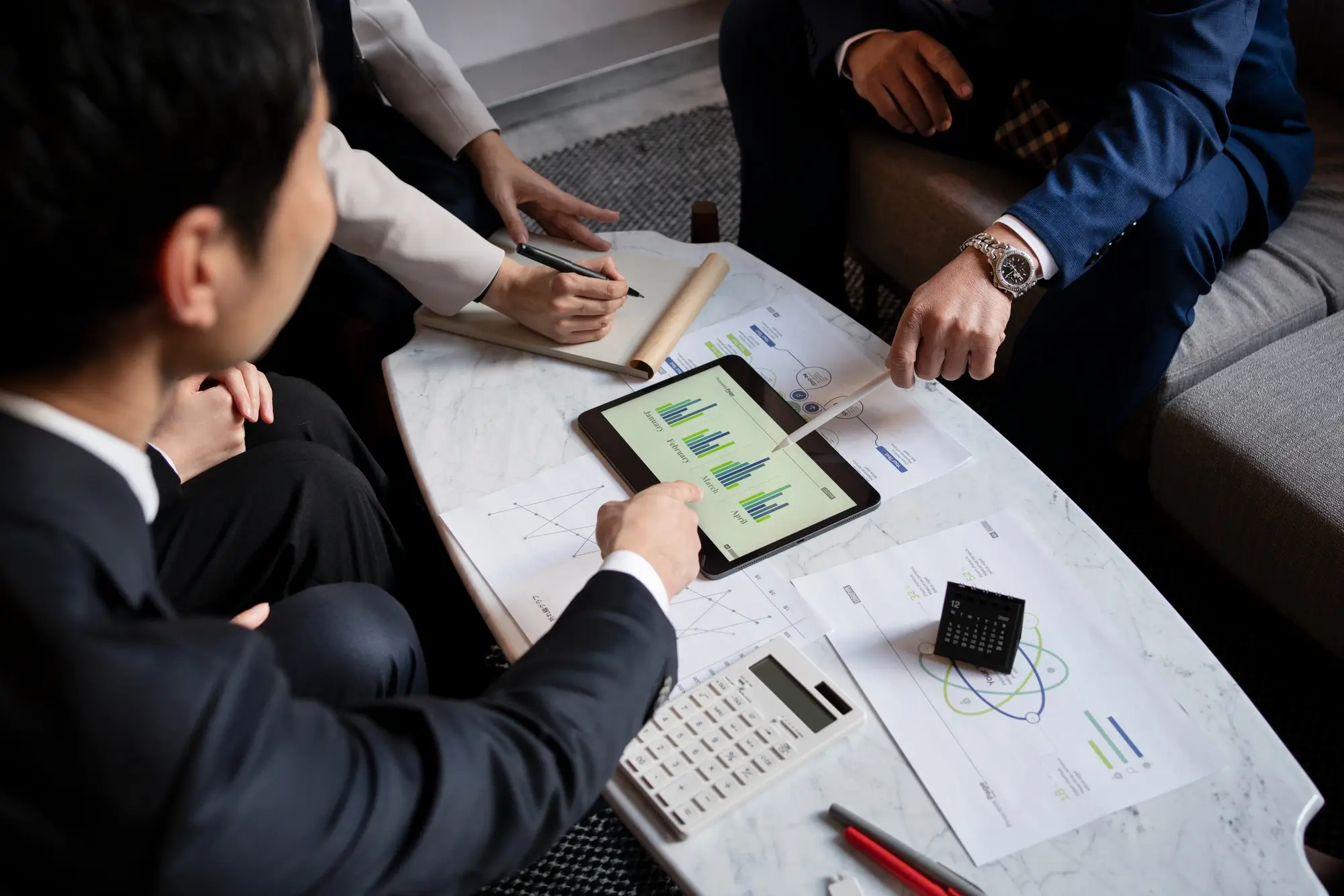 Table with papers, an ipad, and hands pointing at these materials