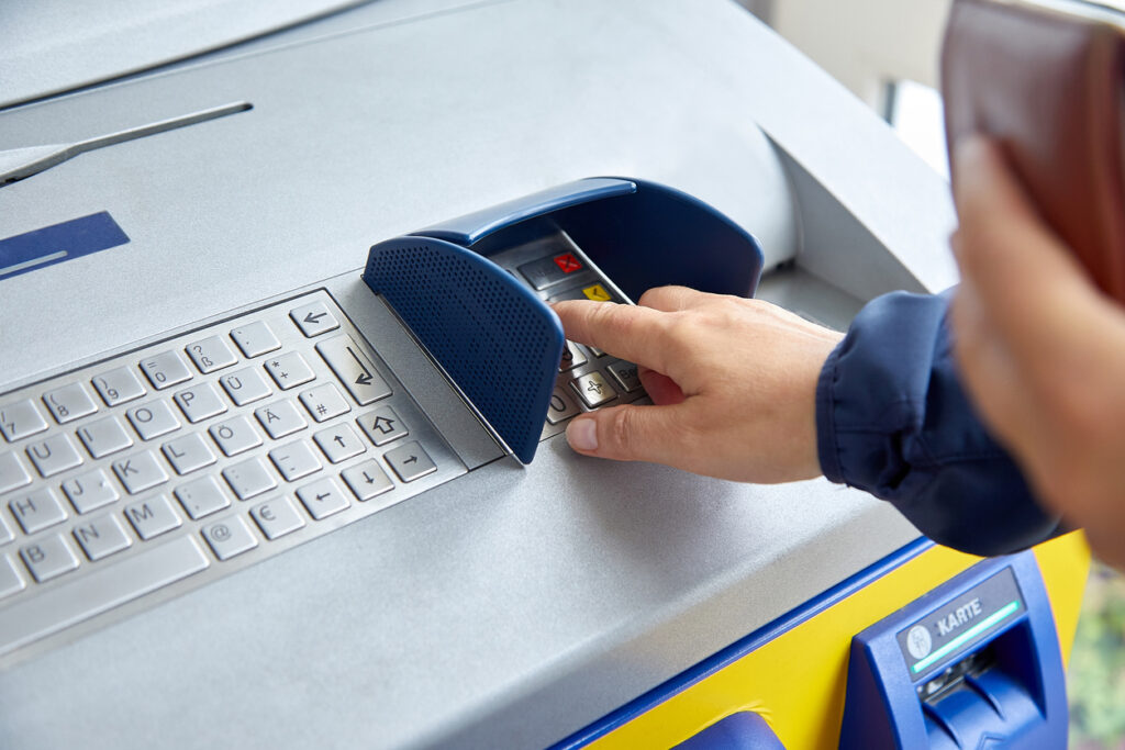 A female hand dials a personal code on the ATM keyboard openly. The concept of lack of caution, carelessness, money transfers and theft of personal information. Close-up