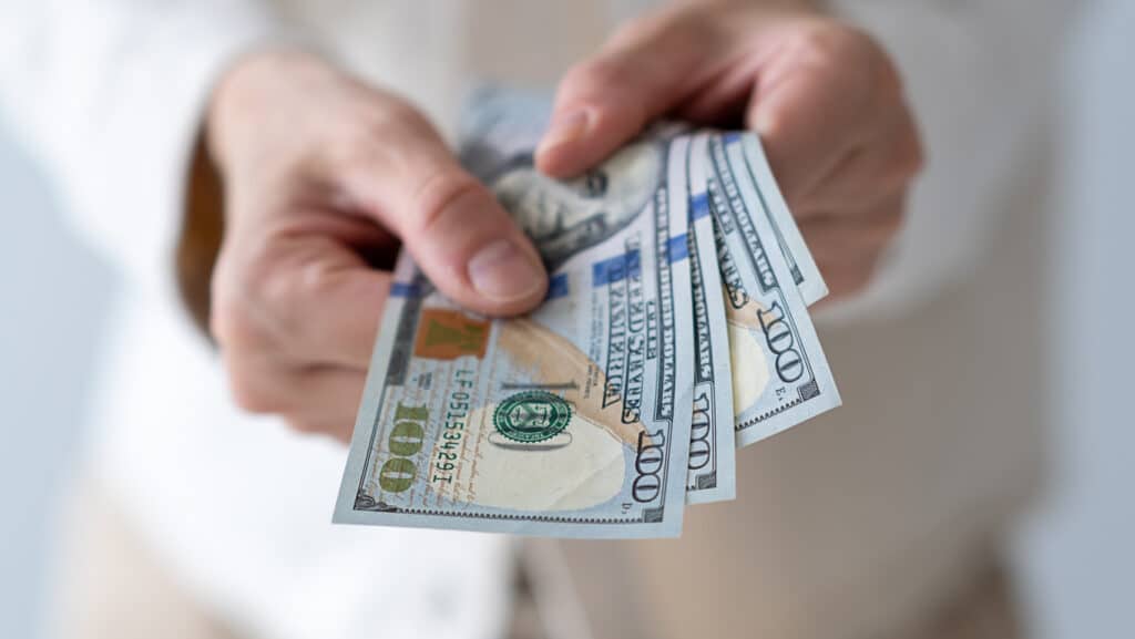 Hands handing over hundred dollar bills