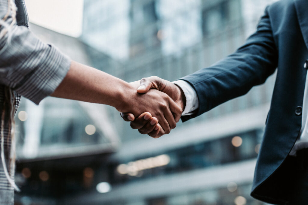 Two business persons shaking hands standing outside stock photo
